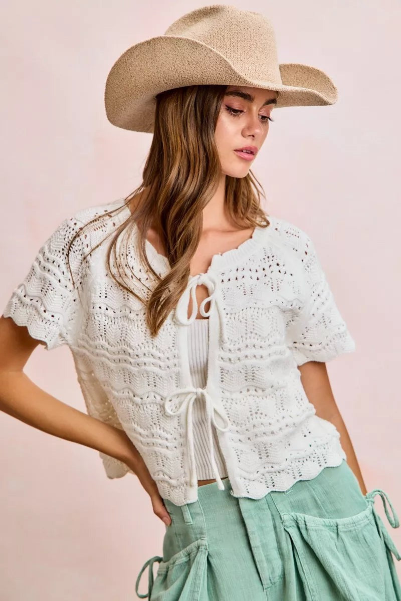 Model wearing a JUST-JEN BOUTIQUE ivory pointelle knit cardigan with bow-tie closures and short puff sleeves