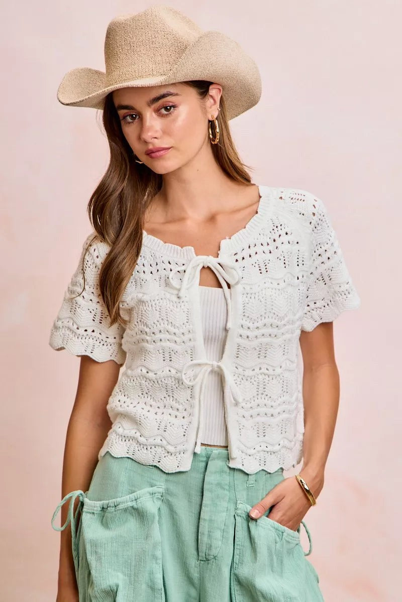 Model wearing a JUST-JEN BOUTIQUE ivory pointelle knit cardigan with puff sleeves and bow-tie front in a boho style.