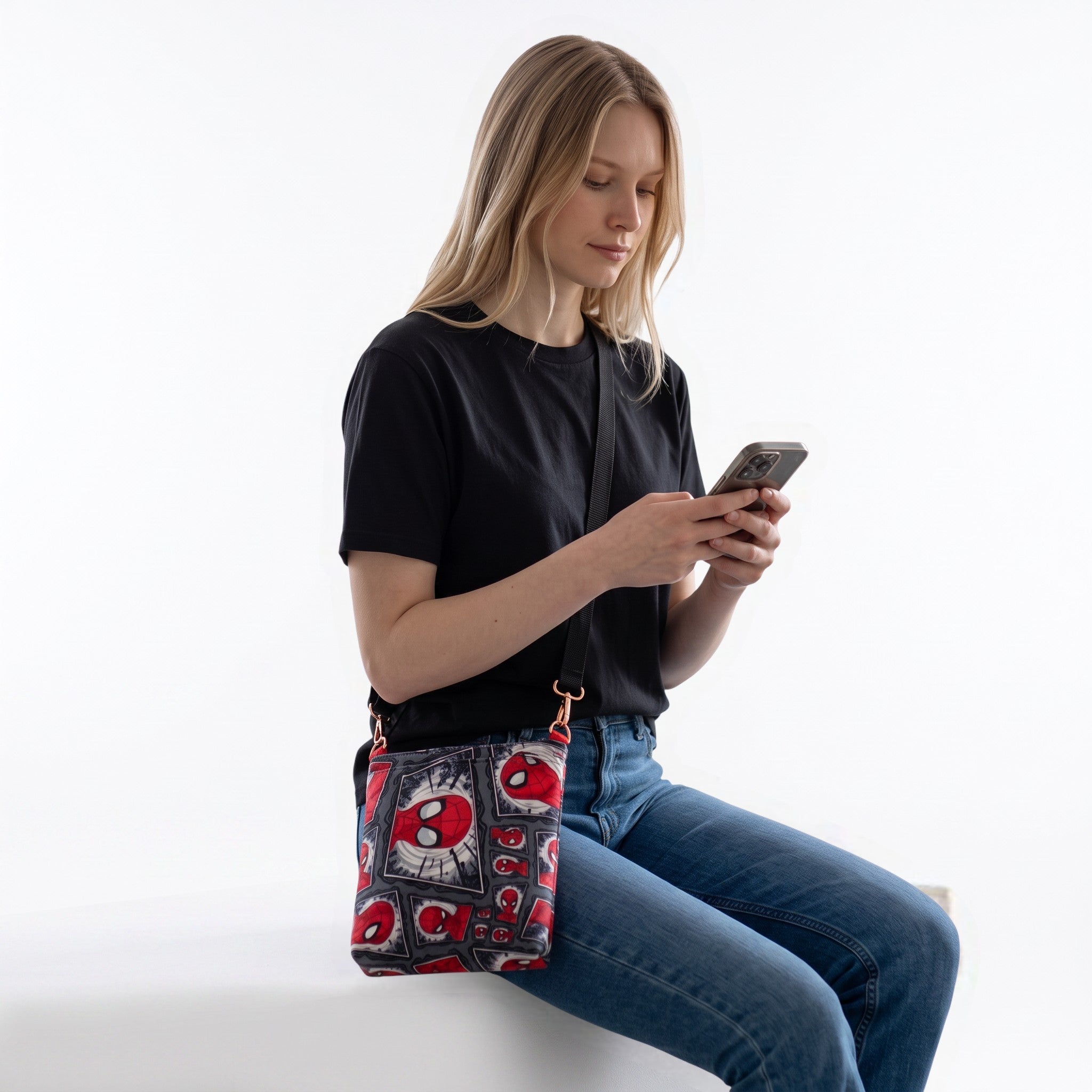 JUST-JEN BOUTIQUE Spider-Man graphic print crossbody bag worn by a woman in a black t-shirt and blue jeans